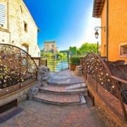 Historic water mills and stone bridge in Borghetto sul Mincio, Italy, with the Mincio River flowing gently beneath, surrounded by lush greenery.