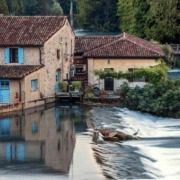 Picturesque village scene in Borghetto sul Mincio, with small stone houses featuring terracotta roofs and colorful shutters lining the riverbanks.