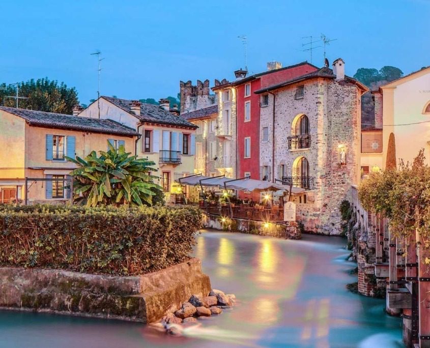 The small houses of Borghetto sul Mincio, feature picturesque stone facades and terracotta roofs, nestled beside the serene waters of the Mincio River.