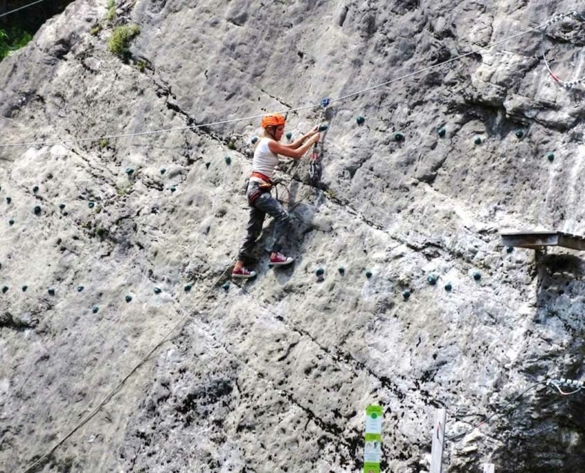 A woman climbing a rock at Elias Adventure Park.