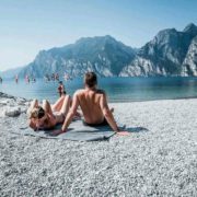 People relaxing and watching windsurfers in the beach of Torbole, Lake Garda.